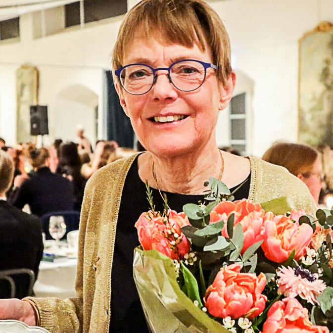 Porträtt av agronomen Stina Olofsson som håller blombukett i famnen.