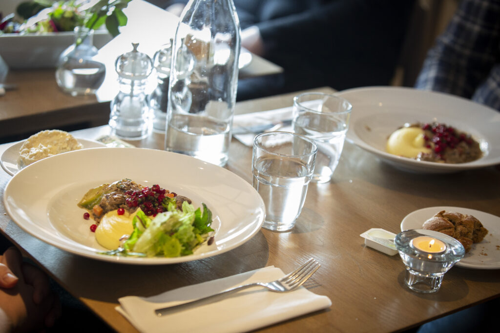 Lunchmat och dukning med vattenglas och vattenflaska på ett bord.